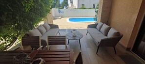A patio area with a pool, outdoor furniture, and a view of the surrounding buildings.
