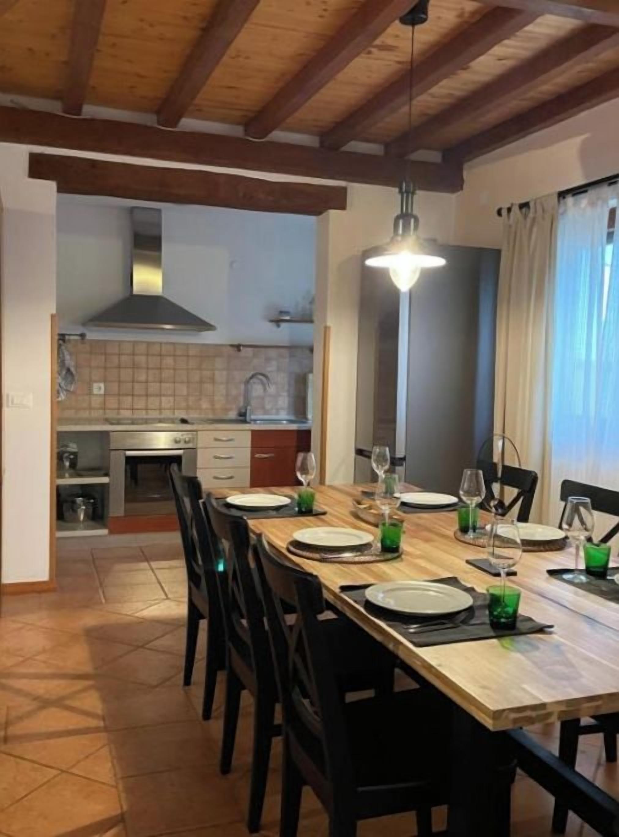 A dining area with a wooden table set for four, black chairs, and a hanging light fixture.