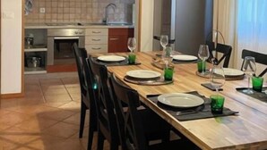 A dining area with a wooden table set for four, black chairs, and a hanging light fixture.
