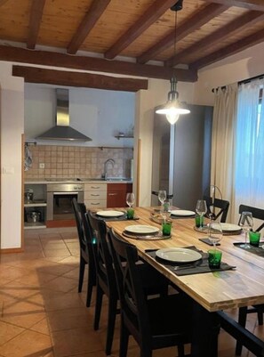 A dining area with a wooden table set for four, black chairs, and a hanging light fixture.