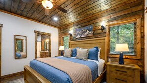 A wooden-paneled bedroom with a large bed, two bedside tables, and a ceiling fan. - Pickleball, Pool, Splash Fountain, Clubhouse, Walking Trails, Pet-Friendly (Broken Bow)