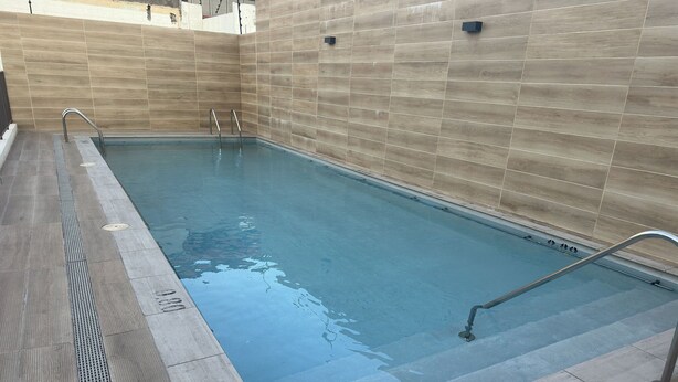 A swimming pool with a tiled border and a metal ladder. - Oceana Suites Vicuña Mackena (Santiago)
