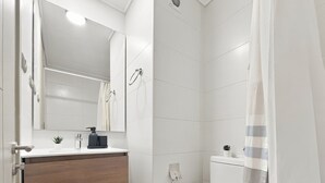 A modern bathroom with a white sink, mirror, and toilet. - Oceana Suites Vicuña Mackena (Santiago)
