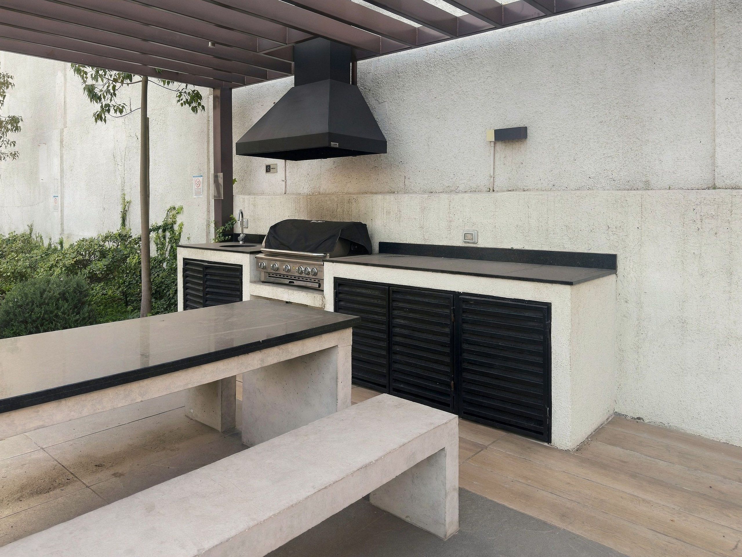 An outdoor kitchen with a grill, a bench, and a table.