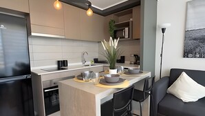 Eine moderne Küche mit einer zentralen Kochinsel, schwarzen Stühlen, einer Couch und einer Stehlampe.