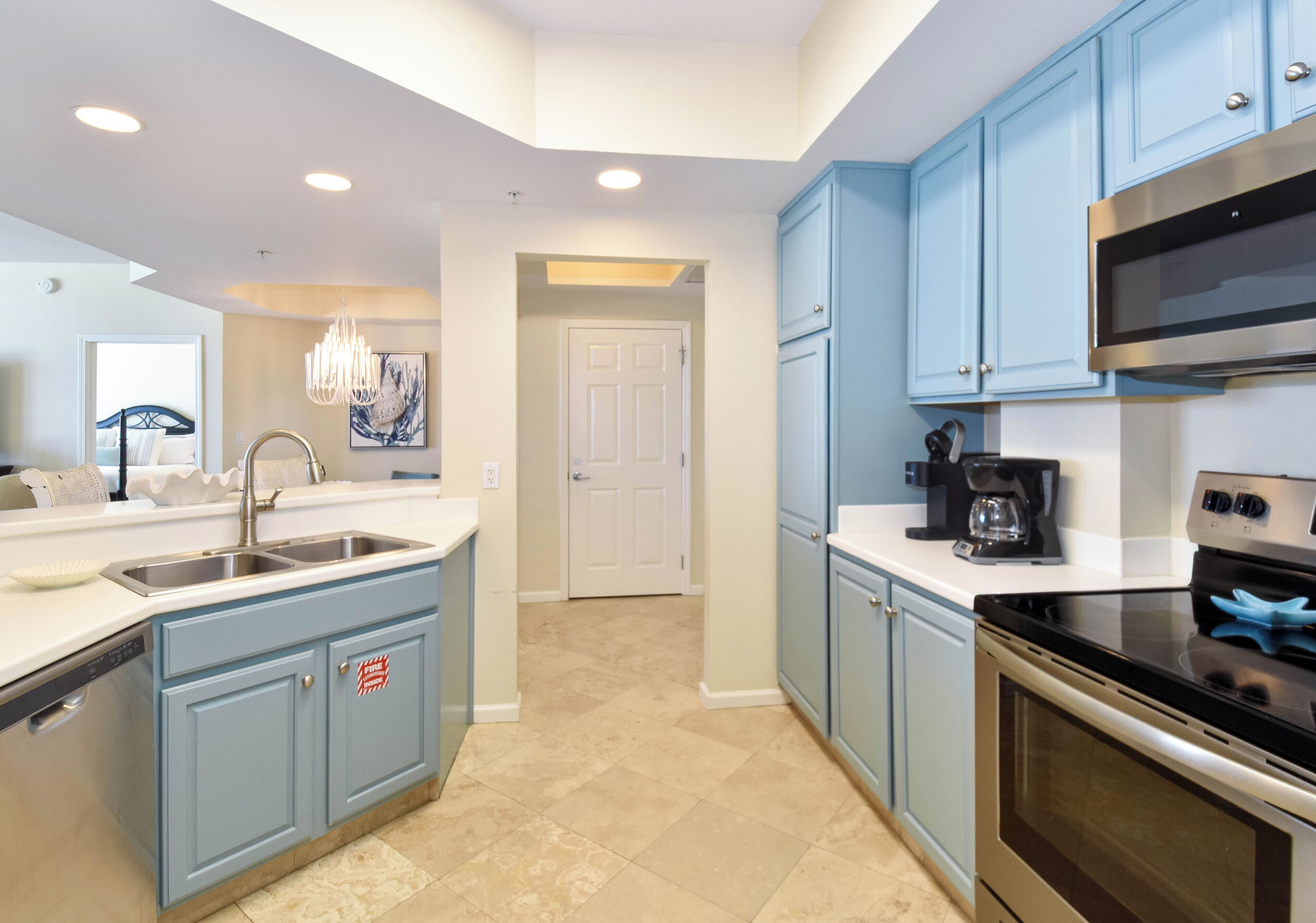 A modern kitchen with blue cabinets, a stainless steel sink, and a built-in oven.