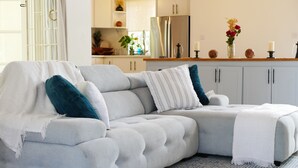 Una sala moderna con un sofá seccional gris, un plaid blanco y almohadones decorativos.