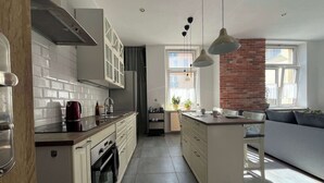 A modern kitchen with white cabinets, a central island, and a brick accent wall.