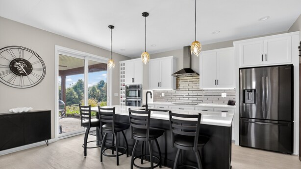 A modern kitchen with a central island, black bar stools, stainless steel appliances, and pendant lighting. - Peaceful Secluded Wausau Retreat 3 Bedroom Home (Wausau)
