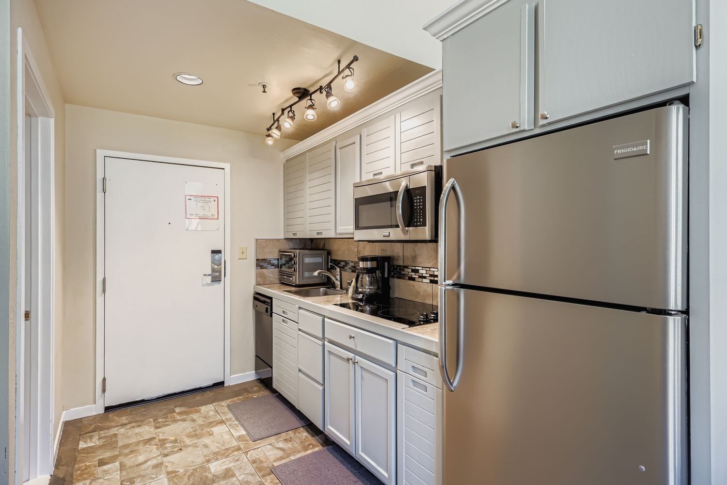 A compact kitchen with a stainless steel refrigerator, a microwave, and a coffee maker.