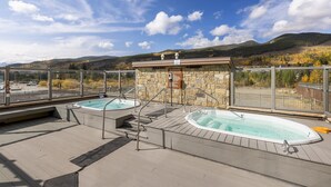 Eine Dachterrasse mit zwei Whirlpools und einem Steinhaus mit einem Schild.