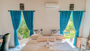A bedroom with a bed, two bedside tables, a desk, and curtains.