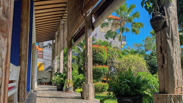 A wooden deck with potted plants and a view of a building with a red roof.