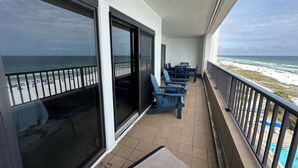 Un balcon avec vue sur la plage, une piscine et un espace repas avec chaises et tables.