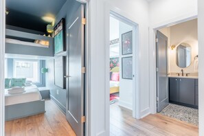 Ein modernes Schlafzimmer mit Etagenbett, begehbarem Kleiderschrank und einem Badezimmer mit großem Spiegel.