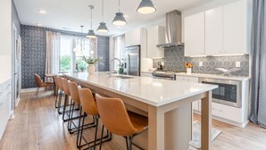 A modern kitchen with a large island, pendant lights, and a view of the outdoors. - Luxe Group Stay With Hot Tub Rooftop Lounge (Nashville)
