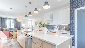 A modern kitchen with a central island, pendant lighting, and a backsplash with a geometric pattern. - Luxe Group Stay With Hot Tub Rooftop Lounge (Nashville)