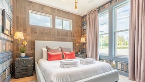 A bedroom with a large bed, two bedside tables, a nightstand, a window with curtains, and a wall with wooden paneling. - Luxe Group Stay With Hot Tub Rooftop Lounge (Nashville)