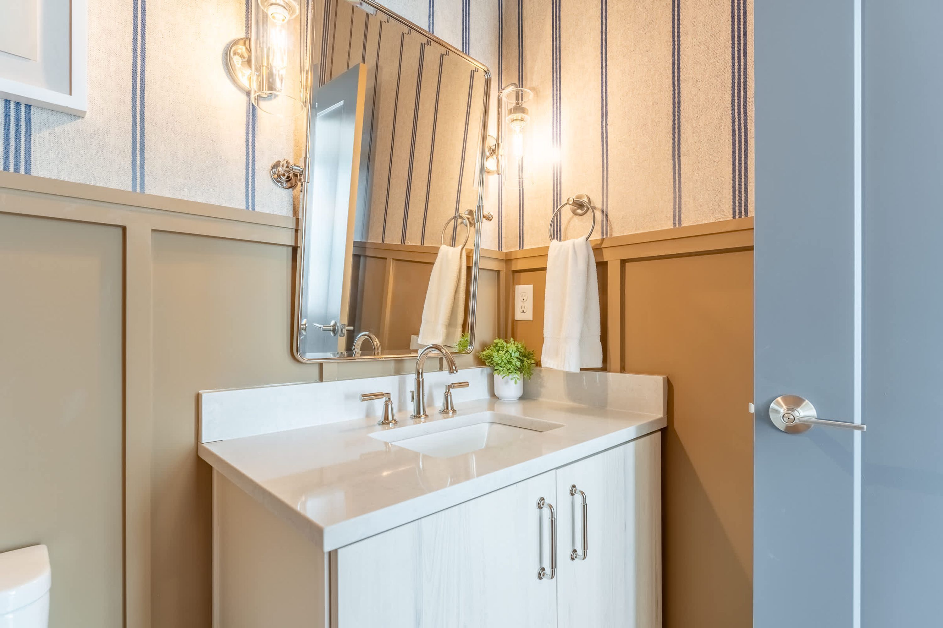 A bathroom with a white sink, two faucets, a mirror, and a towel rack.