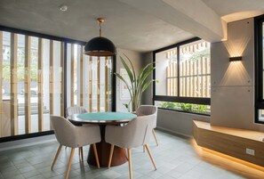 Un espace repas moderne avec une table ronde, quatre chaises, un luminaire suspendu et un banc en bois.
