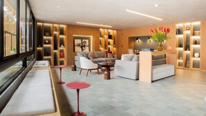 A modern hotel lobby with a seating area, a coffee table, and a bookshelf. - w Comfortable 2BR Stay in Miraflores (Lima)