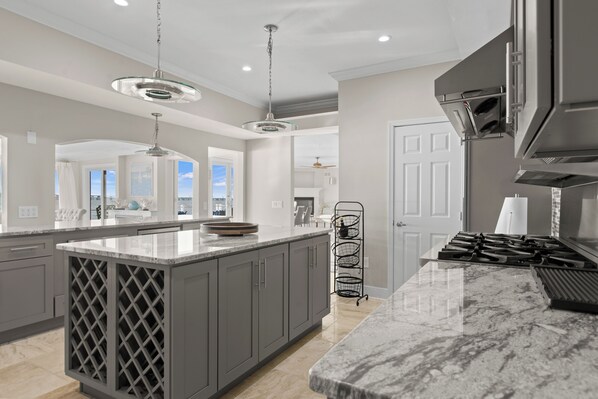 A modern kitchen with grey cabinetry, a marble countertop, and pendant lighting. - Kent Island Waterfront Retreat (Stevensville)