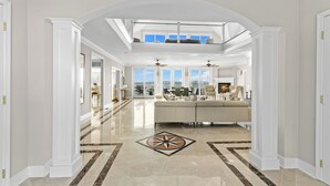 Un interior espacioso con techo alto, una zona de estar central y ventanas amplias que ofrecen vistas del exterior.