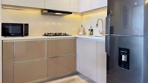 A modern kitchen with white cabinets, a stainless steel refrigerator, a built-in microwave, a gas stove, and a water dispenser. - w Sunlit Loft w Balcony in Santa Barbara (Bogotá)