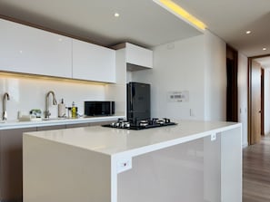 Una cocina moderna con armarios blancos, una isla central, un microondas integrado y una estufa a gas.