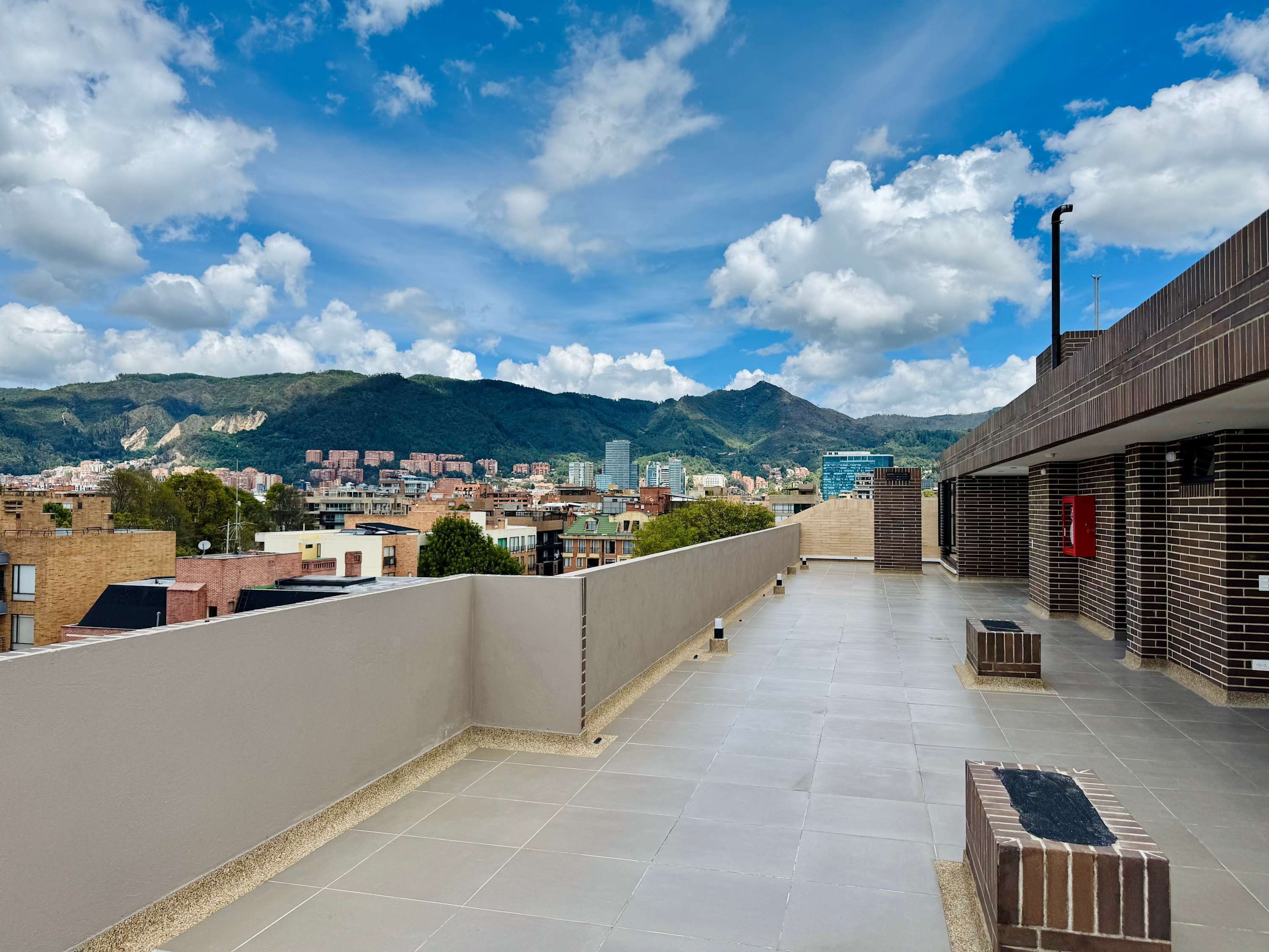 Une terrasse sur le toit offrant une vue sur le paysage urbain et les montagnes.