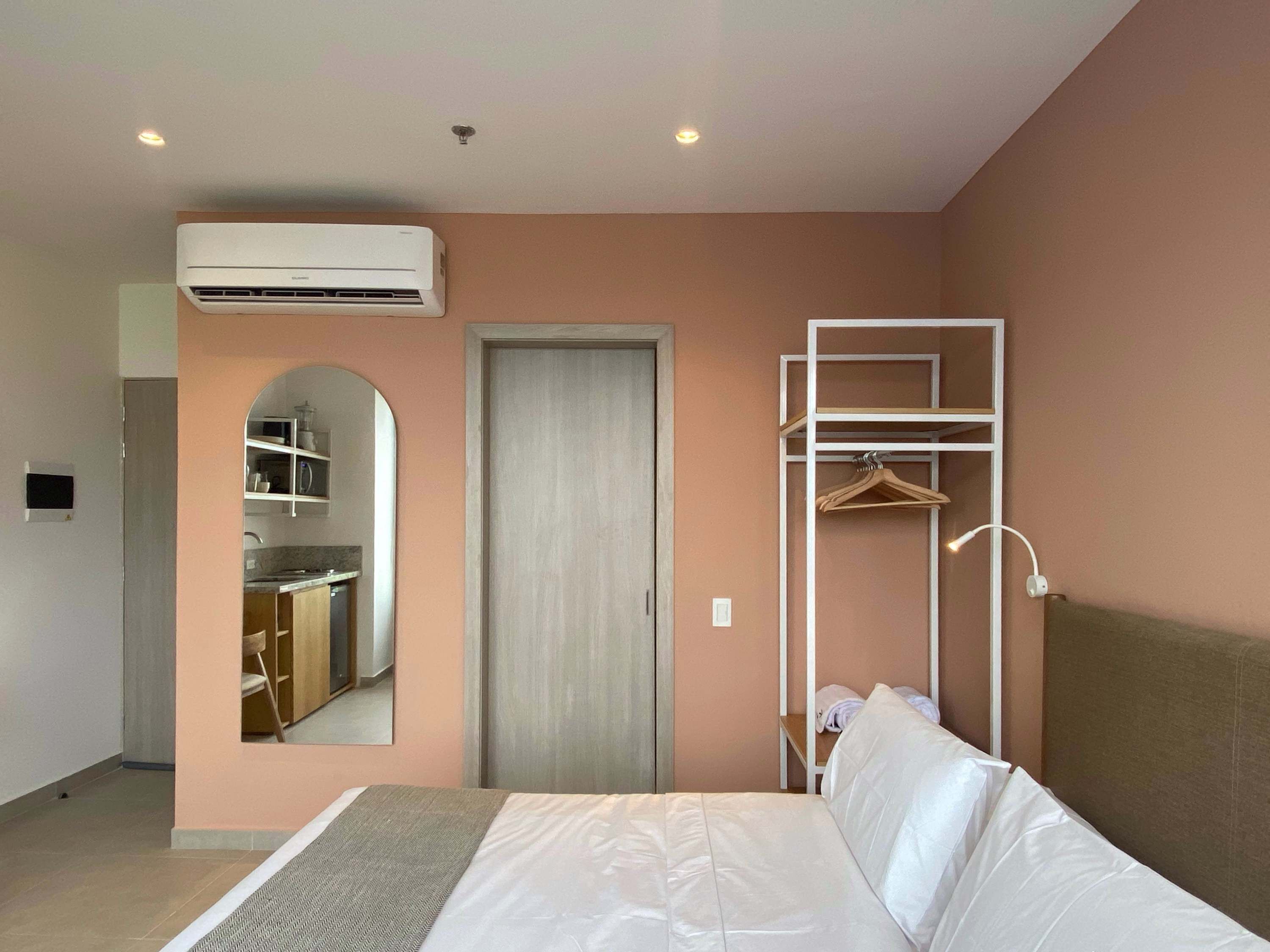 A bedroom with a bed, a wardrobe, a mirror, and an air conditioning unit.
