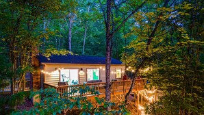 Eine Holzhütte mit einer Terrasse, umgeben von Bäumen und Lichterketten.