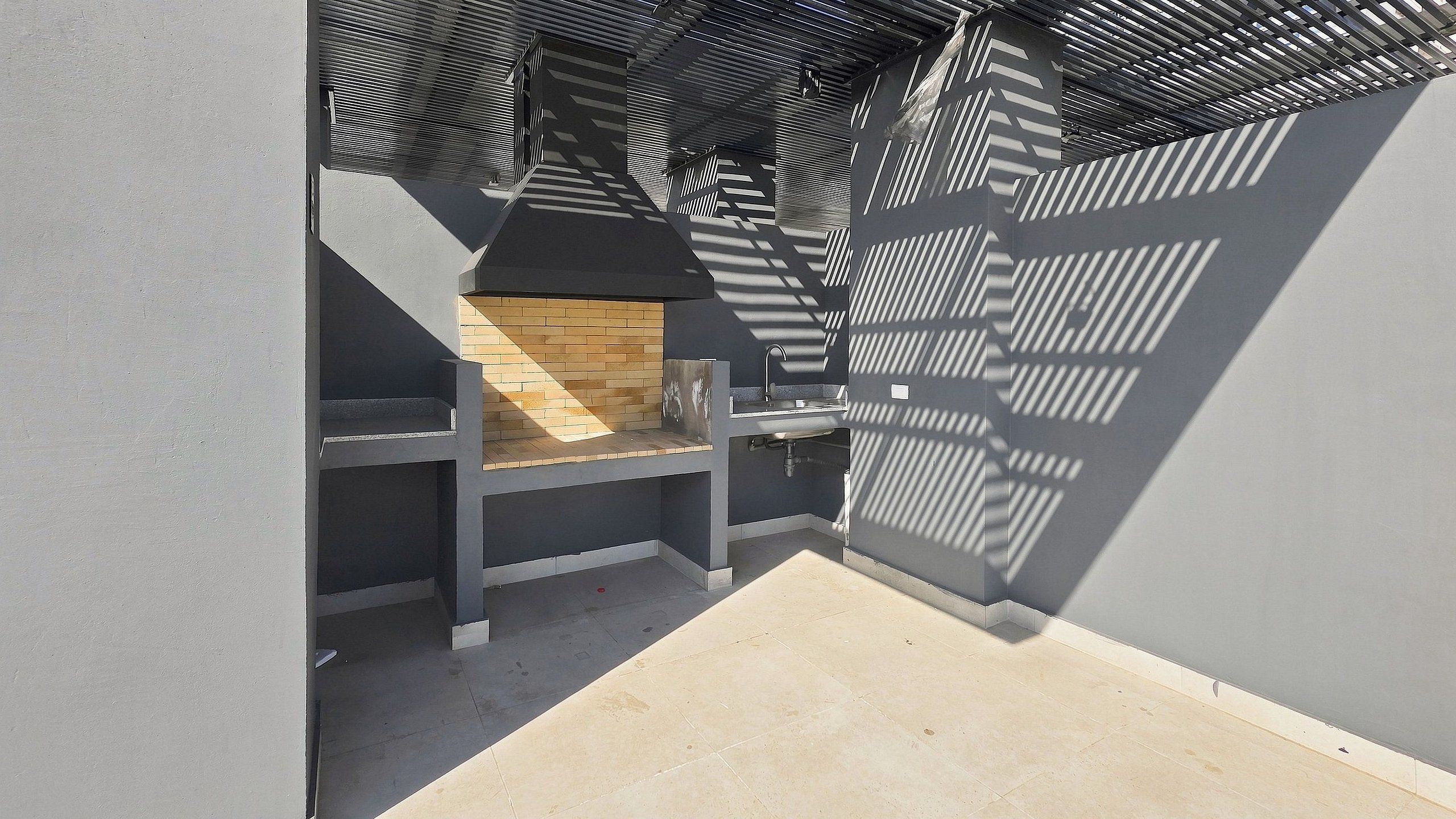 Un coin de pièce avec un sol carrelé, un mur en briques et une structure métallique qui projette des ombres.