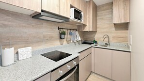 Una cocina moderna con microondas integrado, un lavamanos de acero inoxidable y una estufa a gas.