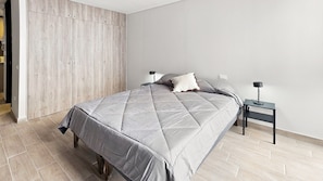Ein Schlafzimmer mit einem Bett, zwei Nachttischen, einem Kleiderschrank und einer Tür.