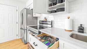 A modern kitchen with white cabinetry, stainless steel appliances, and a built-in dishwasher drawer.