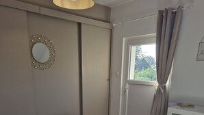 A bedroom with a bed, bedside table, and a window with curtains.