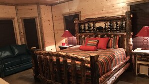 Ein schlafzimmer im Stil einer Blockhütte mit einem hölzernen Himmelbett, einem grünen Sofa und zwei roten Lampen.