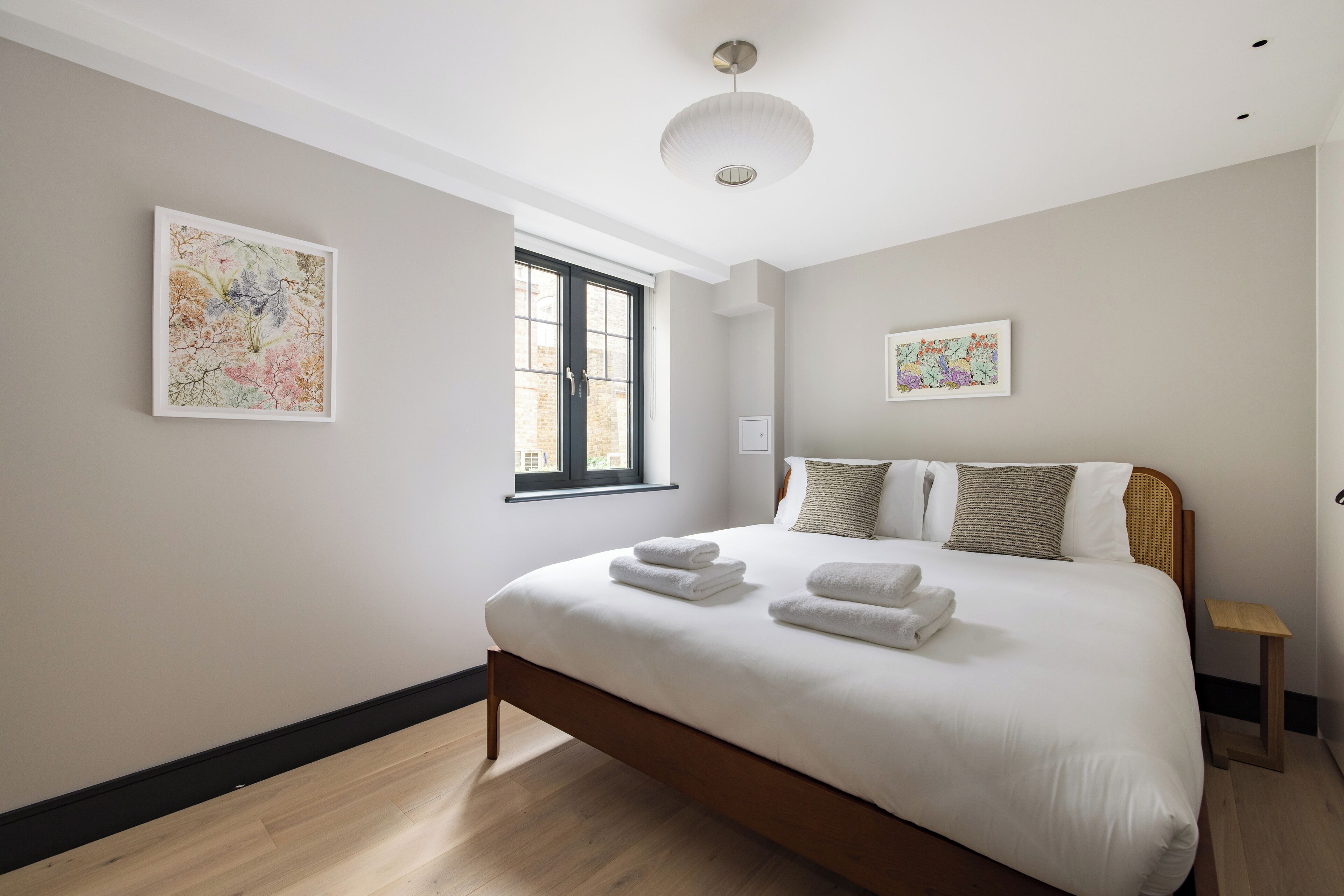 A modern bedroom with a large bed, two pillows, a bedside table, and artwork on the walls.