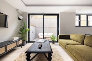 Un salon moderne comprenant un canapé, une table basse, un téléviseur et une porte-fenêtre coulissante donnant sur un balcon.