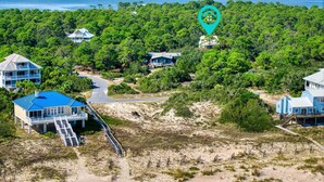 Una proprietà costiera con diverse case, un sentiero per accedere alla spiaggia e una fitta foresta.