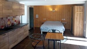 Un dormitorio moderno con una cama grande, un armario de madera y una pequeña mesa con sillas.
