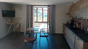 Una cocina moderna con comedor, televisor montado en la pared y vistas al exterior.