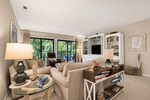 A living room with a sofa, coffee table, and TV stand. - Walk-to-Beach Condo with 3 Patios & Pool (Hilton Head Island)