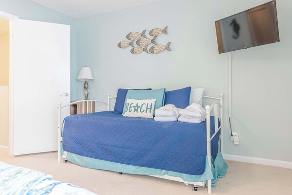 Un dormitorio con cama, televisor montado en la pared y una decoración de peces en la pared.