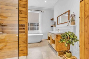 Une salle de bain moderne avec une baignoire sur pieds, des meubles en bois, un grand miroir et une plante en pot.