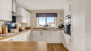 Une cuisine moderne avec des armoires blanches, un plan de travail en bois et une fenêtre donnant sur l’extérieur.