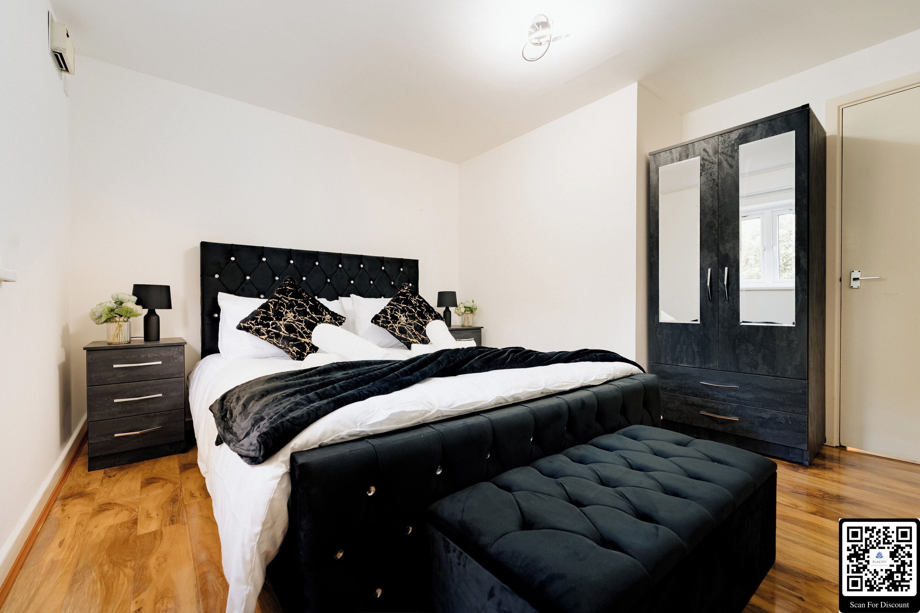 Una camera da letto moderna con un letto grande, un armadio scuro e un comodino con una lampada.