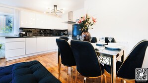 Una cocina moderna con armarios blancos, una mesa de comedor con sillas y un jarrón con flores.