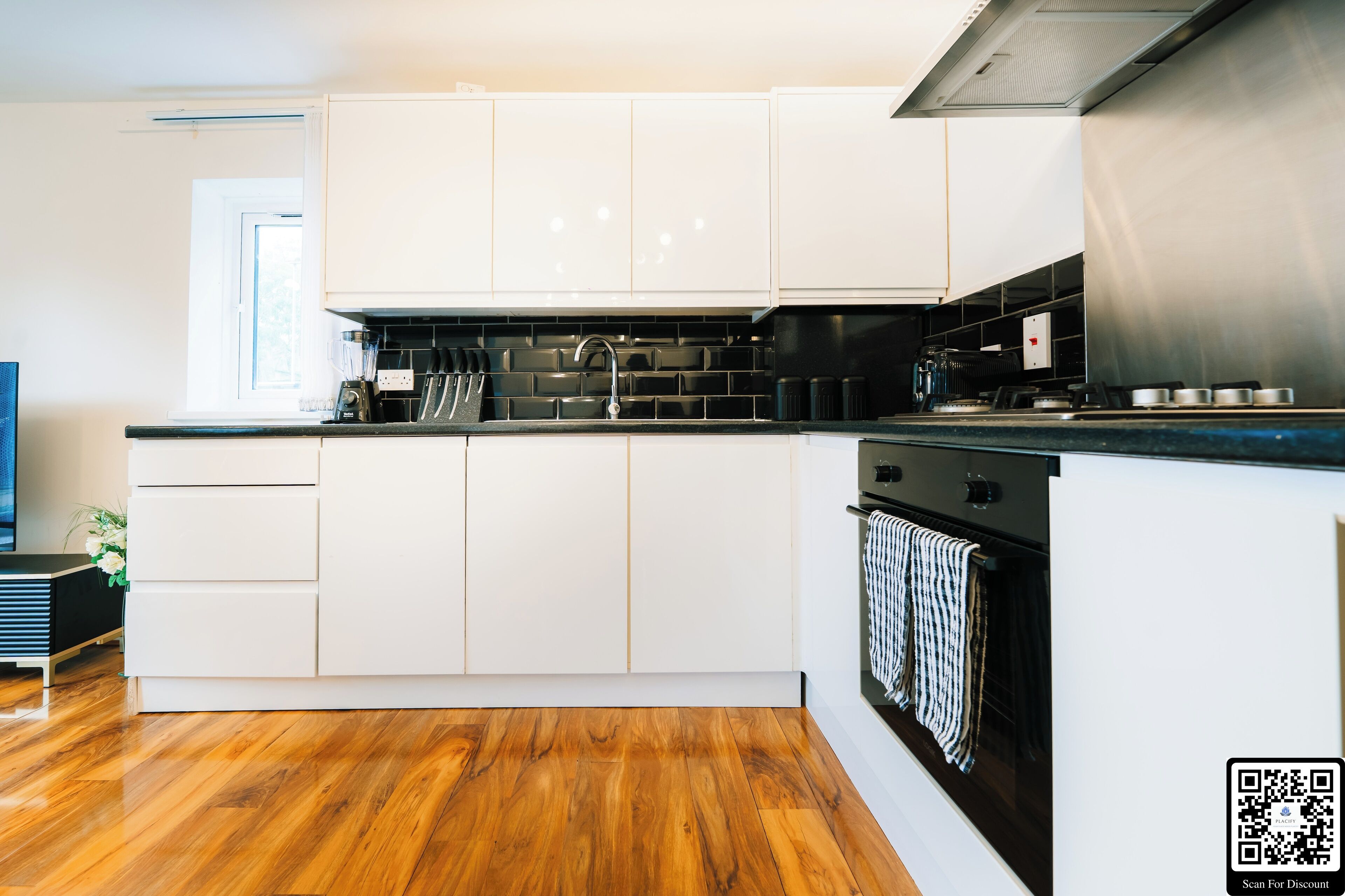 A modern kitchen with white cabinets, a black countertop, and a stainless steel oven.